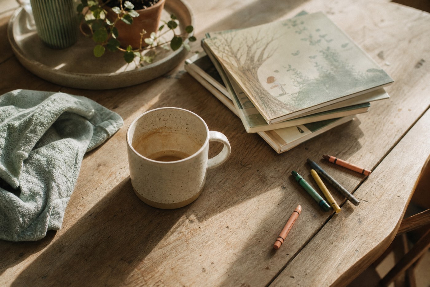 A sunlit kitchen table with everyday family objects, warm and lived in
